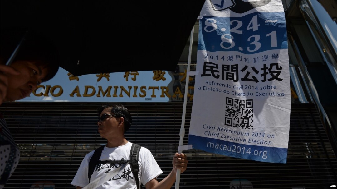 A volunteer displays a banner on a street to raise awareness of an unofficial referendum in Macau, Aug. 24, 2014. 