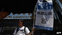 A volunteer displays a banner on a street to raise awareness of an unofficial referendum in Macau, Aug. 24, 2014. 