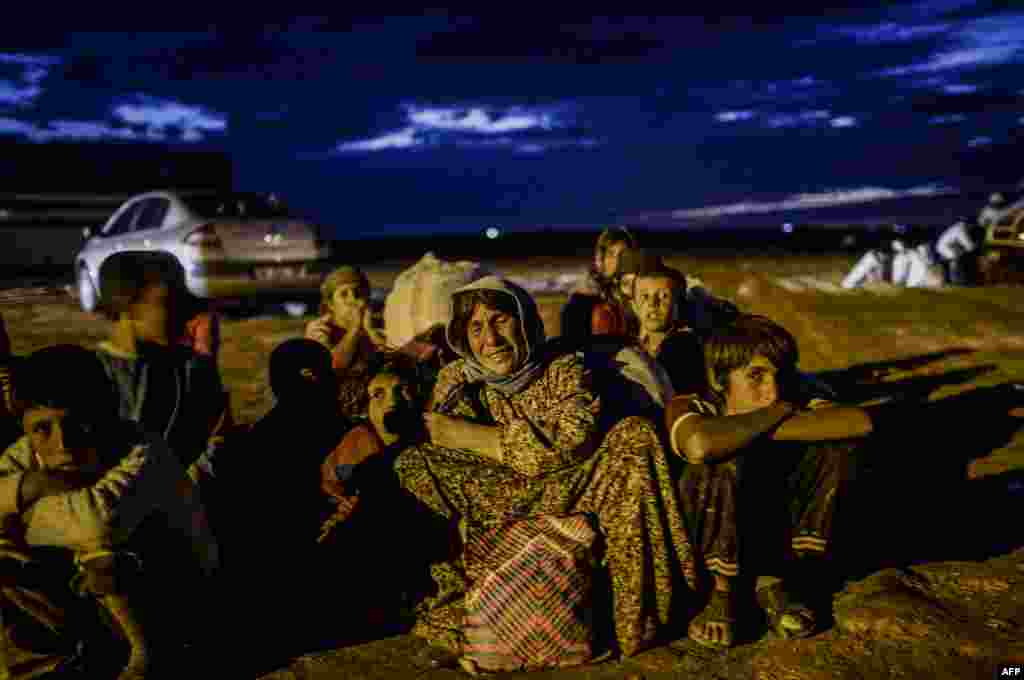 A Syrian Kurdish family waits after crossing the border between Syria and Turkey after several mortars hit both sides near the southeastern town of Suruc in Sanliurfa province, Sept. 29, 2014. 