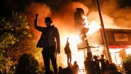 Protestors demonstrate outside of a burning fast food restaurant, May 29, 2020, in Minneapolis. Protests over the death of George Floyd, a black man who died in police custody Monday, broke out in Minneapolis for a third straight night.