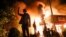 Protestors demonstrate outside of a burning fast food restaurant, May 29, 2020, in Minneapolis. Protests over the death of George Floyd, a black man who died in police custody Monday, broke out in Minneapolis for a third straight night.