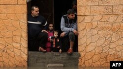 Palestinian residents, stranded in an inundated house, stare out of the entrance of their home, following torrential rains that hit the Jabalia refugee camp in the northern Gaza strip, Jan. 16, 2022.