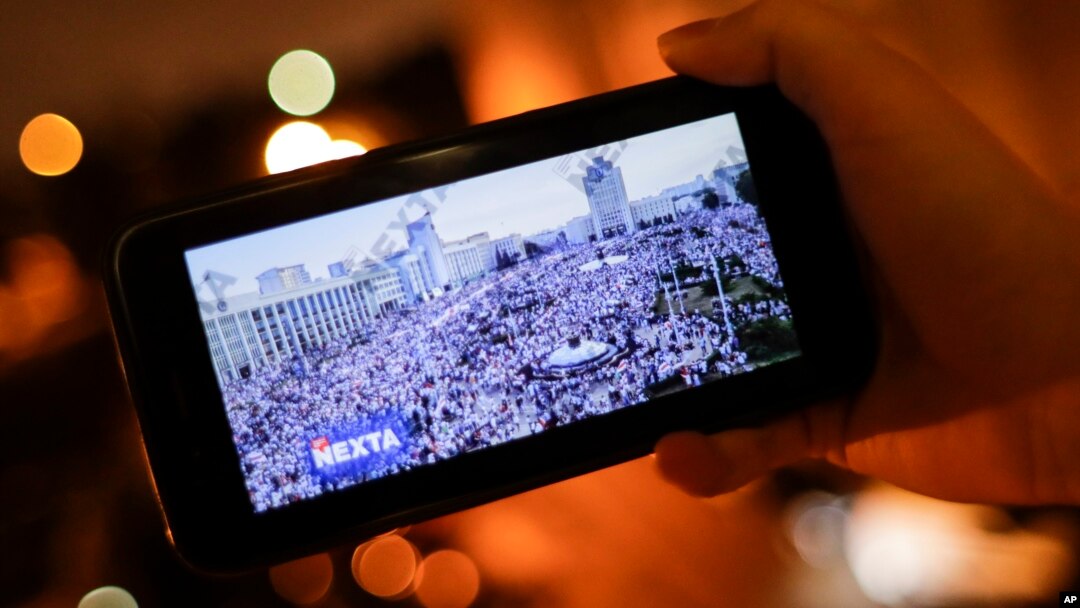 FILE - A man looks at Telegram channel NEXTA Live on his smartphone showning a rally against President Alexander Lukashenko, in Minsk, Belarus, Aug. 19, 2020. 