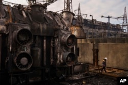 Un trabajador camina frente a un transformador que quedó destruido tras un reciente ataque con misiles rusos en la planta de energía de DTEK en Ucrania, el 28 de noviembre de 2024. (Foto AP/Evgeniy Maloletka)