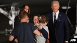 Presidente dos Estados Unidos, Joe Biden, e vice-presidente, Kamala Harris, assistem ao abraço entre a jornalista Alsu Kurmasheva e familiares na Base Andrews, em Maryland, 1 agosto 2024