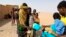 In this April 25, 2020 photo provided by IOM Niger, some of nearly 100 Nigeriens arrive in Assamaka, Niger, on foot from Algeria and now must be quarantined for two weeks at the remote Sahara border settlement.