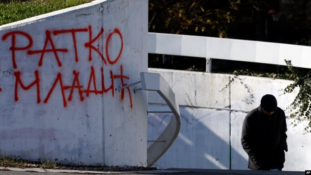 A man walks by graffiti that in Cyrillic reads "Ratko Mladic," in Belgrade, Serbia, Nov. 28, 2017