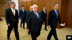 Syrian Foreign Minister Walid Moallem, center, and his Chinese counterpart Wang Yi, right, arrive for a press briefing at China's Ministry of Foreign Affairs in Beijing, Thursday, Dec. 24, 2015.