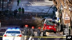 Penyelidik pada 26 Desember 2020, berjalan di dekat lokasi ledakan di Nashville, Tennessee. Ledakan Jumat dini hari ini menghancurkan jendela, merusak bangunan dan menyebabkan beberapa orang terluka. (Foto: AP)