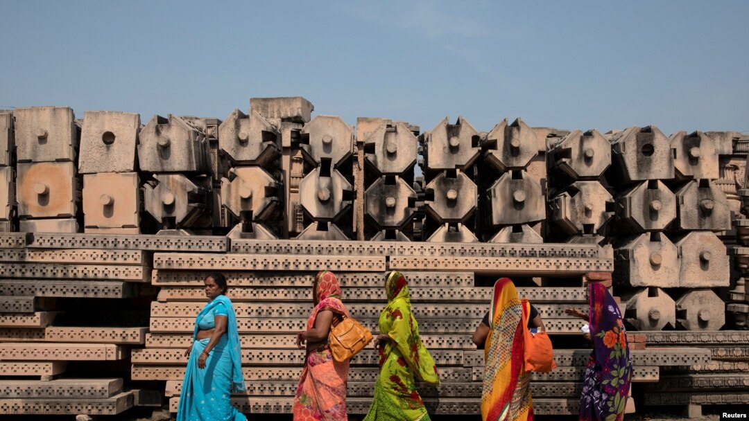 Devotees walk past the pillars that Hindu nationalist group Vishva Hindu Parishad (VHP) say will be used to build a Ram temple at the disputed religious site in Ayodhya, India, Oct. 22, 2019.