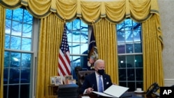 조 바이든 미국 대통령이 20일 백악관 집무실에서 마스크를 쓴채 행정명령에 서명하고 있다. 