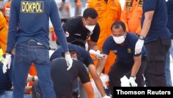 Rescatistas indonesios revisan una bolsa para cadáveres del vuelo Sriwijaya Air Flight SJ182 que se estrelló en el mar, en el puerto de la Terminal Internacional de Contenedores en Yakarta, Indonesia. Enero 10, 2021.