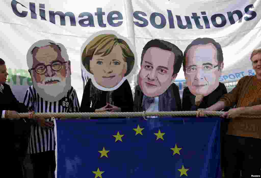 Environmental protesters wear masks depicting (L-R) European Climate Action and Energy Commissioner Miguel Arias Canete, German Chancellor Angela Merkel, Britain&#39;s PM David Cameron and French President Francois Hollande as activists stage a &quot;tug-of-war&quot; between polluting fossils fuels and renewable energy during a protest outside the European Union Council in Brussels, Belgium.