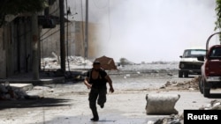 A man runs for cover during clashes between Free Syrian Army fighters and Syrian Army soldiers in the Salah al-Din neighborhood of central Aleppo August 4, 2012.