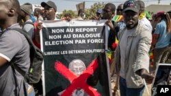 FILE — Supporters of the Aar Sunu Senegal opposition collective display a banner reading - 'No to postponement, no to dialogue, election by force', on a street, in Dakar, on February 17, 2024. 