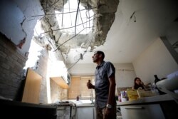Adi Vaizel looks at damage to his house after it was hit by a rocket launched from the Gaza Strip this week, in Ashkelon, Israel, May 20, 2021. News reports said Israel's security cabinet and Hamas on Thursday had approved a tentative cease-fire.
