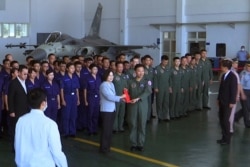 Taiwan President Tsai Ing-wen, center left, poses for photos with airmen near a Taiwan Indigenous Defense Fighter jet displayed during a visit to the Penghu Magong military air base in outlying Penghu Island, Taiwan, Sept. 22, 2020.