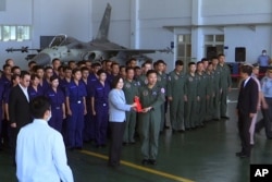 Taiwan President Tsai Ing-wen, center left, poses for photos with airmen near a Taiwan Indigenous Defense Fighter jet displayed during a visit to the Penghu Magong military air base in outlying Penghu Island, Taiwan, Sept. 22, 2020.