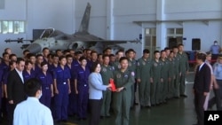 Taiwan President Tsai Ing-wen, center left, poses for photos with airmen near a Taiwan Indigenous Defense Fighter jet displayed during a visit to the Penghu Magong military air base in outlying Penghu Island, Taiwan, Sept. 22, 2020.
