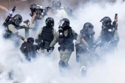 FILE - Police in riot gear move through a cloud of smoke as they detain a protester at the Hong Kong Polytechnic University.