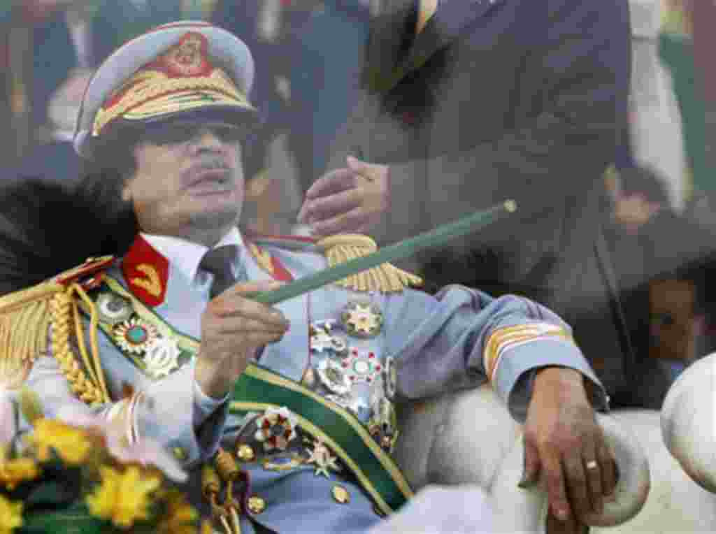 FILE - In this Sept. 1, 2009 file photo, Libyan leader Moammar Gadhafi gestures with a green cane as he takes his seat behind bulletproof glass for a military parade in Green Square, Tripoli, Libya. The International Criminal Court prosecutor has asked ju