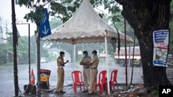 Policemen enforcing a lockdown to curb the spread of coronavirus stand beneath a rain shelter in Kochi, Kerala state, India, May 16, 2021.