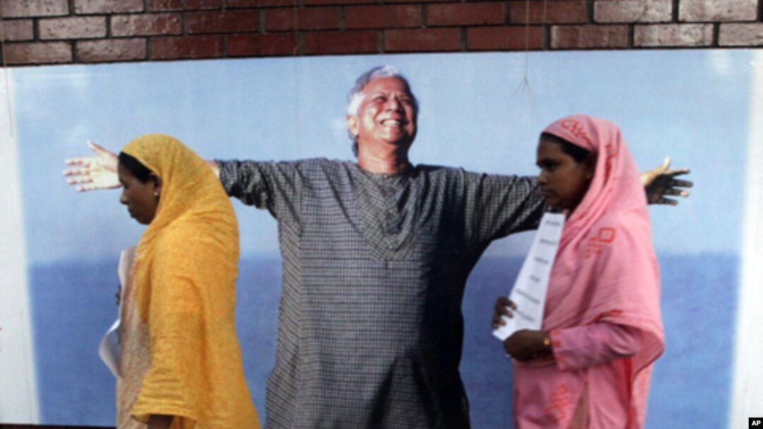 Employees of Grameen Bank walk in front of a portrait of Nobel laureate and bank founder Mohammad Yunus, Dhaka, Bangladesh, March 8, 2011.