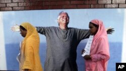 Employees of Grameen Bank walk in front of a portrait of Nobel laureate and bank founder Mohammad Yunus, Dhaka, Bangladesh, March 8, 2011.