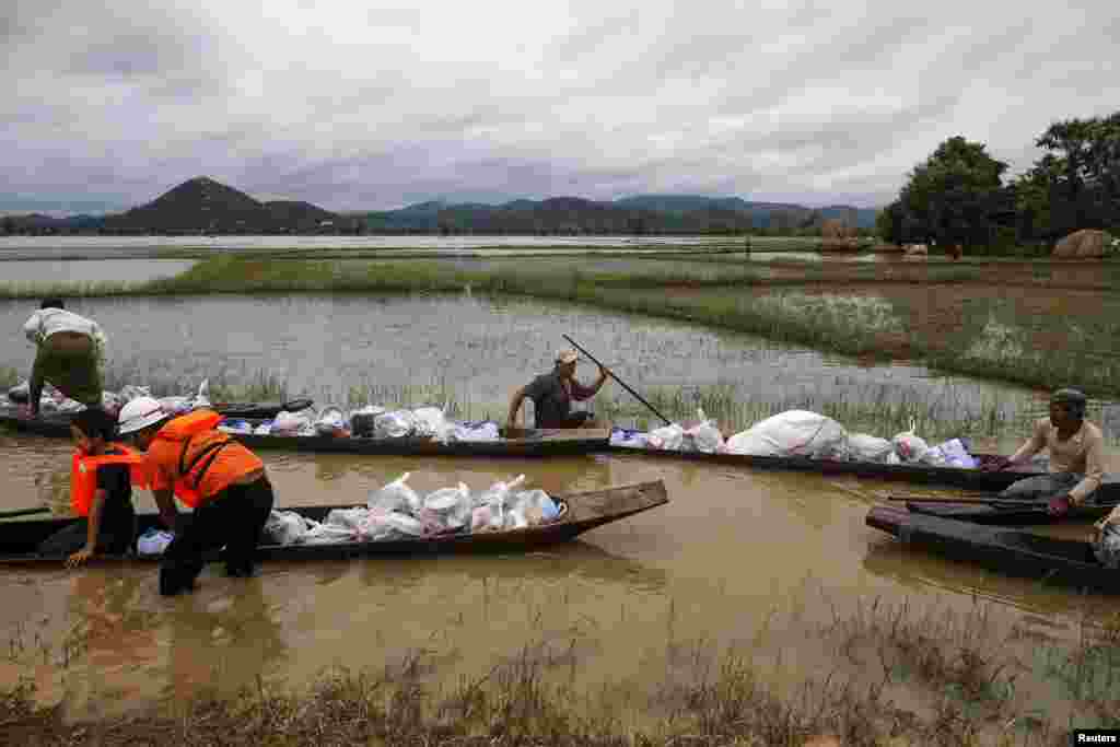 Residents ride a boat on a flooded area as they transport aid for their village at Kawlin township, Sagaing...