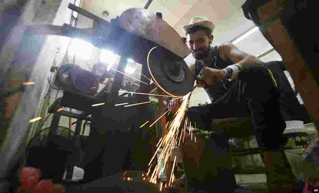 A Palestinian man sharpens a knife that will be used to slaughter cattle or cut meat during the Muslim festival of sacrifice Eid al-Adha, in a workshop in Gaza City, July 28, 2020.