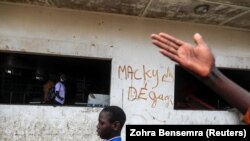 Un garçon passe devant un graffiti sur lequel il est écrit "Macky dégage" faisant référence au président sénégalais Macky Sall à Dakar, le 5 mars 2021.