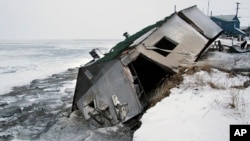 FILE - In this Dec. 8, 2006, file photo, Nathan Weyiouanna's abandoned house at the west end of Shishmaref, Alaska, sits on the beach after sliding off during a fall storm in 2005. 