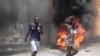 Manifestantes pasan corriendo junto a neumáticos incendiados durante una protesta contra la inseguridad en Puerto Príncipe, Haití, el 7 de agosto de 2023.