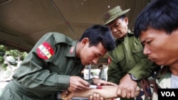 Seorang tentara Burma menyuntikkan obat-obatan kepada korban gempa di Minelin, MInggu (27/3).