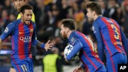 Lionel Messi de Barcelone, au centre, court, balle en main, en compagnie de ses co-équipiers Neymar, à gauche, et Gerard Piqué, après son but sur penalty lors d’un match de la Ligue des champions entre le FC Barcelone et Paris Saint Germain au stade Camp 