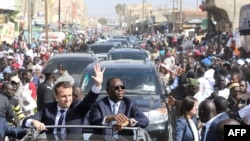 Le président français Emmanuel Macron (à gauche) et le président sénégalais Macky Sall (à droite) saluent la foule depuis leur voiture à Saint-Louis, le 3 février 2018.