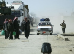 FILE - People enter Iraq from Syria at a border checkpoint in the city of al-Yarubiyah, 600 kms northwest of Baghdad, March 16, 2004.