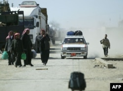 FILE - People enter Iraq from Syria at a border checkpoint in the city of al-Yarubiyah, 600 kms northwest of Baghdad, March 16, 2004.