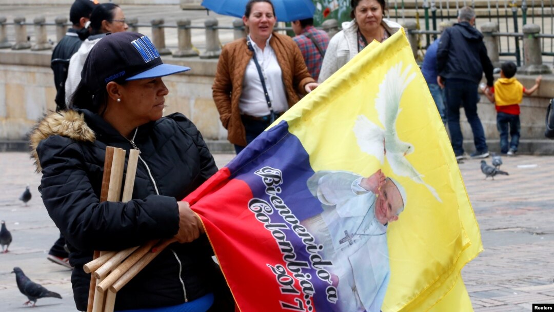 A woman sells flags with the image of Pope Francis outside the Cathedral of Bogota in Bolivar Square, Colombia, Sept. 2, 2017.