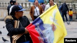 A woman sells flags with the image of Pope Francis outside the Cathedral of Bogota in Bolivar Square, Colombia, Sept. 2, 2017.