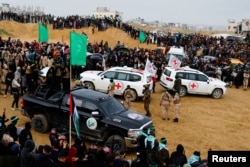 Palestinian militants and members of the Red Cross gather near vehicles on the day Hamas hands over deceased Israeli hostages to the Red Cross, in Khan Younis in the southern Gaza Strip, Feb. 20, 2025.