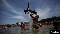 People play at an artificial pond known as piscinao, or big pool, in the northern suburbs of Rio de Janeiro, Brazil, Jan. 8, 2017.