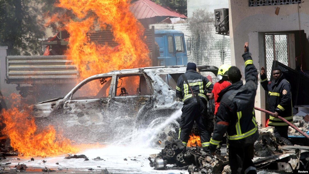 FILE - Somali firemen try to extinguish burning cars at the scene where a car bomb exploded in front of a restaurant in Mogadishu, Somalia, Jan. 29, 2019. 