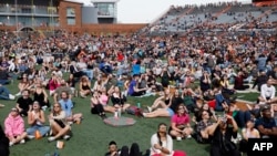 FILE - Spectators look at the solar eclipse through protective eyewear on the football field at Bowling Green State University on April 8, 2023, in Bowling Green, Ohio. 