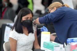 FILE - A woman receives a coronavirus vaccination at Jordan Downs in Los Angeles, California, March 10, 2021.