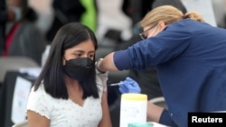 FILE - A woman receives a coronavirus vaccination at Jordan Downs in Los Angeles, California, March 10, 2021. 