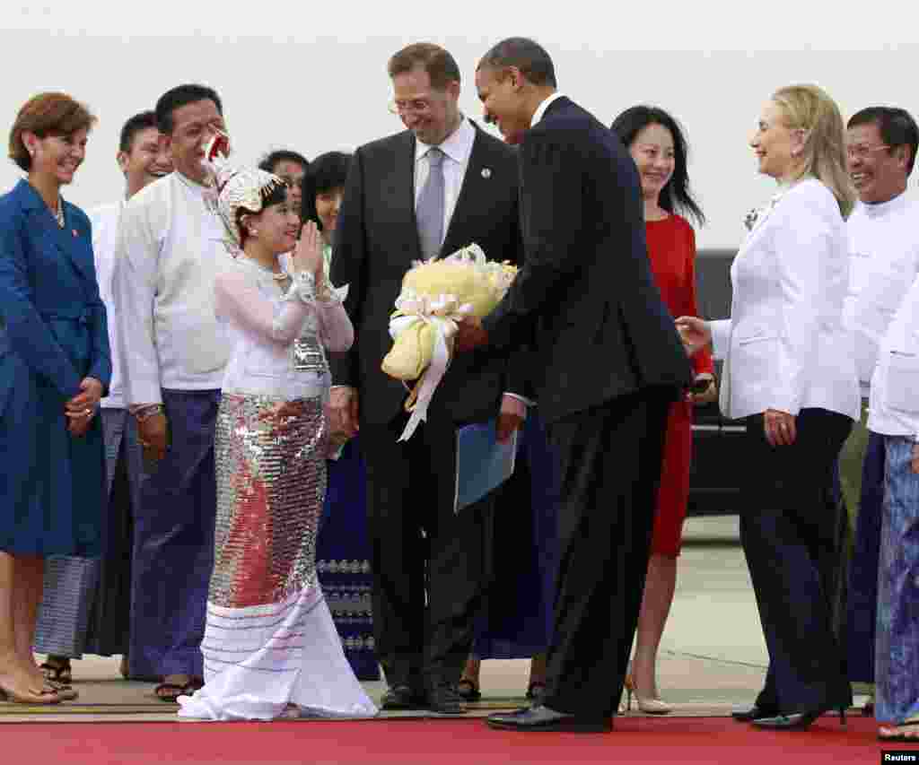 ເດັກຍິງຜູ້ນຶ່ງ ຖ່າຍຮູບ ລຸນຫລັງທີ່ໄດ້ມອບຊໍ່ດອກໄມ້ ໃຫ້ແກ່ປະທານາທິບໍດີ ສະຫະລັດ ທ່ານ Barack Obama (ທີ 4 ຂວາ) ໃນຂະນະທີ່ທ່ານໄປເຖິງ ເດີ່ນບິນສາກົນ​ນະຄອນ​ຢ່າງ​ກຸ້ງ ໃນວັນທີ 19 ພະຈິກ 2012.&nbsp;