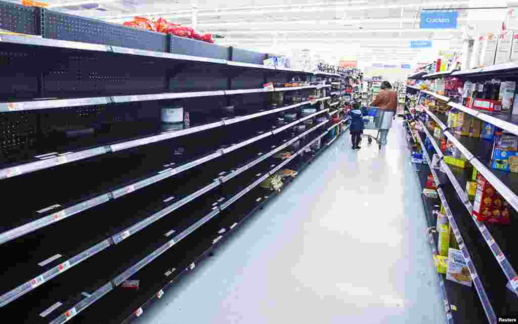 A woman and child walk through an aisle emptied in preparation for Hurricane Sandy, in a Wal-Mart store in Riverhead, New York, October 28, 2012.