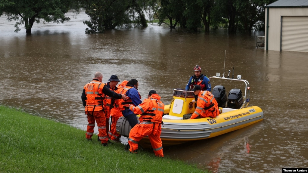 Para petugas membantu seorang dokter gigi mengunjungi pasiennya yang terjebak banjir dari permukiman Windsor ke North Richmond di tengah banjir yang melanda Kota Sydney, Australia, Senin, 22 Maret 2021. (Foto: Loren Elliott/Reuters)