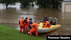 Para petugas membantu seorang dokter gigi mengunjungi pasiennya yang terjebak banjir dari permukiman Windsor ke North Richmond di tengah banjir yang melanda Kota Sydney, Australia, Senin, 22 Maret 2021. (Foto: Loren Elliott/Reuters)